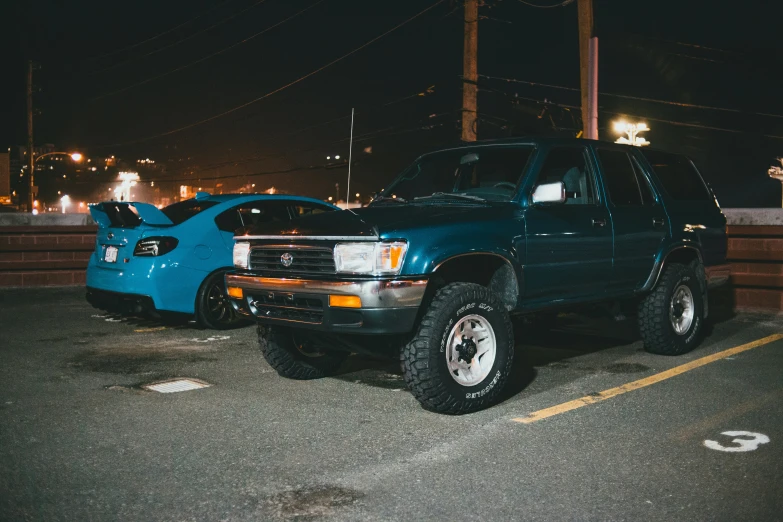two blue cars in parking lot at night
