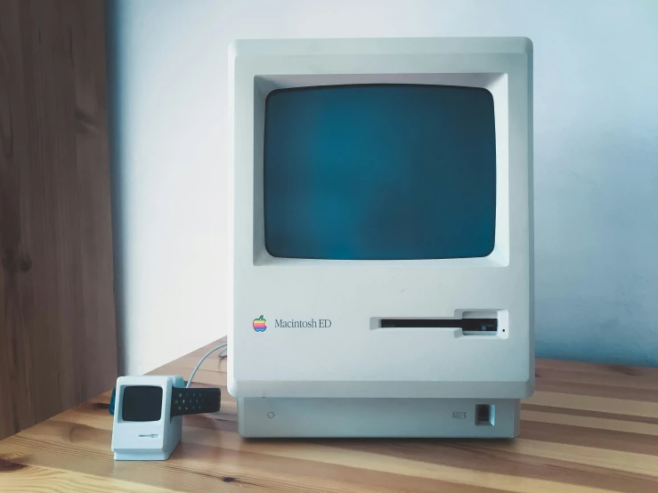 a small computer sits on a table next to a tv