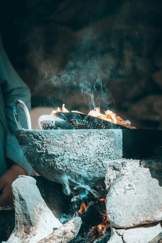 a woman cooking food over a small grill outdoors