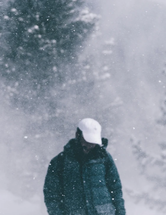 person in black coat and white hat carrying snowboard on snowy ground