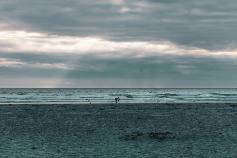 the man stands on the beach watching surfers
