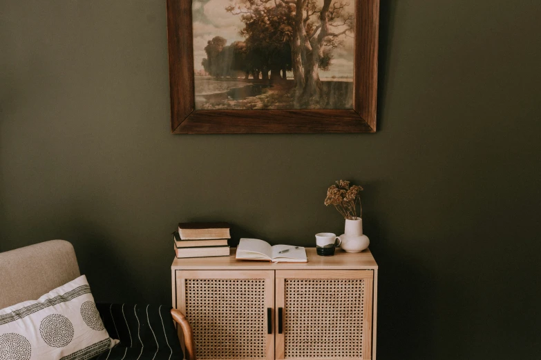 a bookshelf in a green room with a picture hanging on the wall