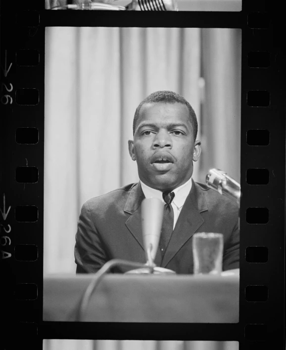 a black and white po of a man with a microphone and film behind him