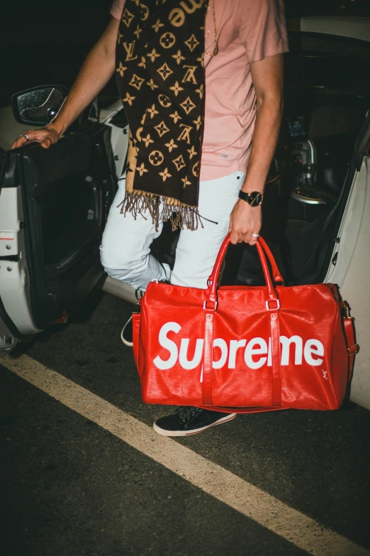 a man holds a large red bag while walking