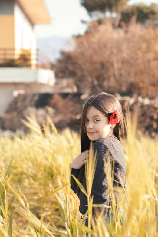 a  smiles as she stands in some tall grass