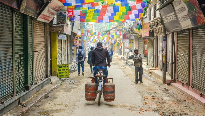 a man rides a bicycle in front of an umbrella covered city street