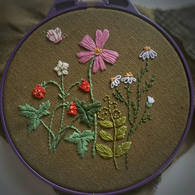 a purple handbag holds a floral cross stitch project