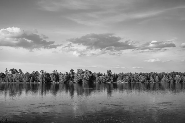 the clouds are gathering above the water by the forest