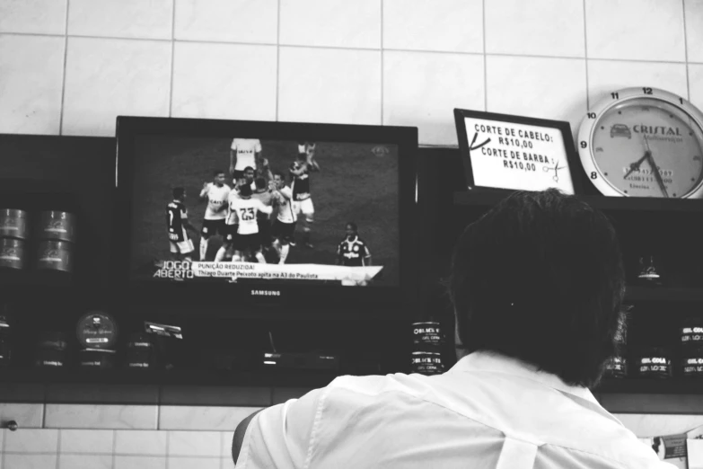 a television in a restaurant with the man watching football on it