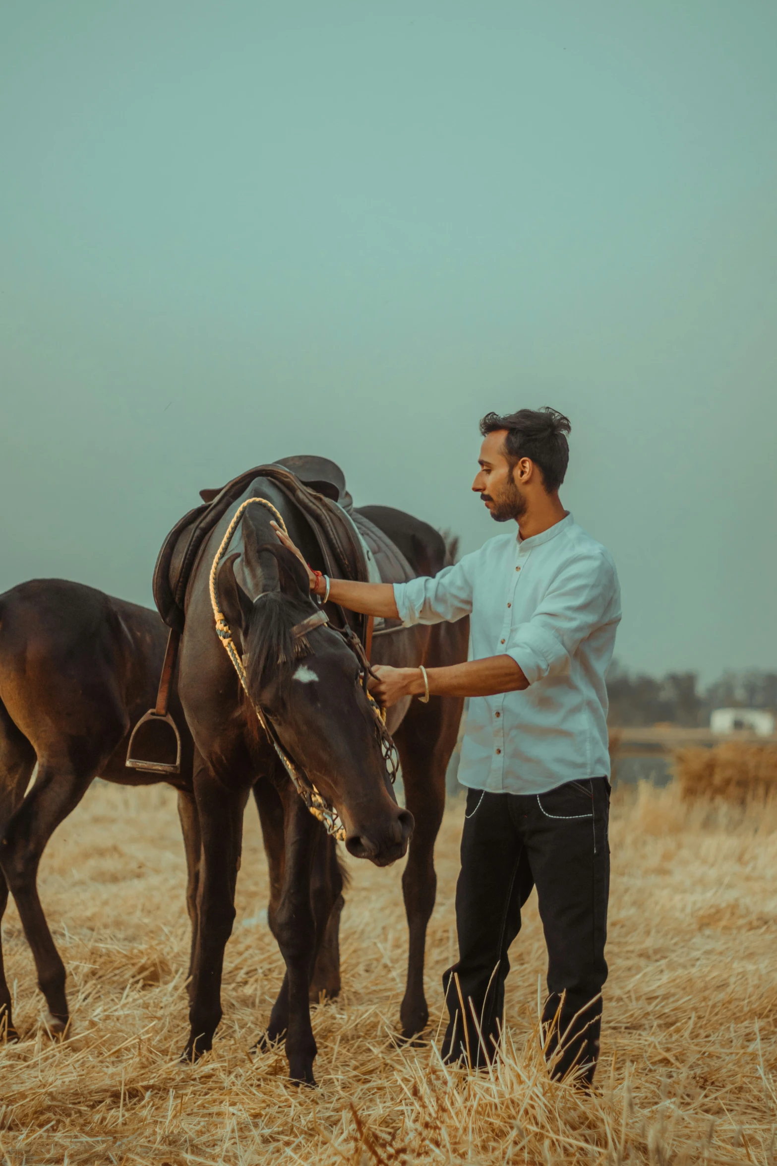 a man is putting the reins on his horse