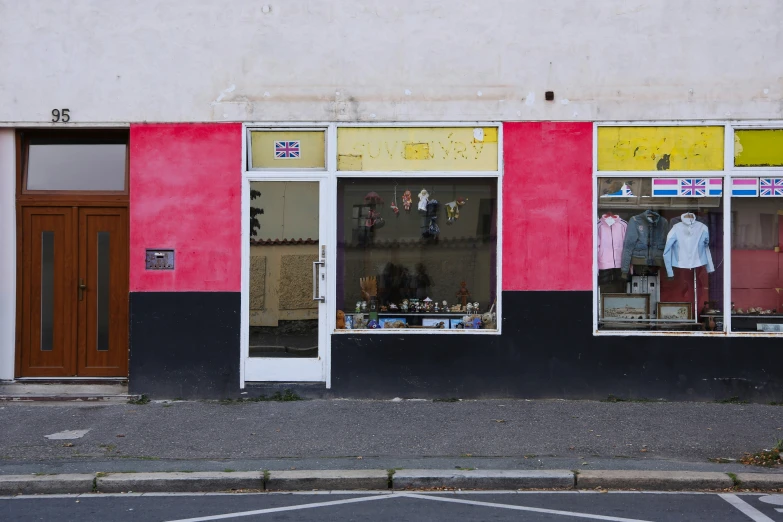 a store front with clothing on display and a car parked outside