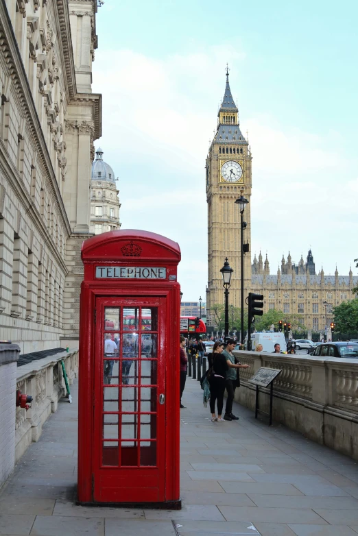 an old fashioned red phone booth is next to big ben