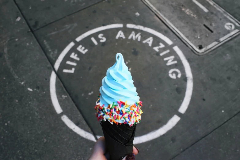 a person holding an ice cream cone with colored sprinkles