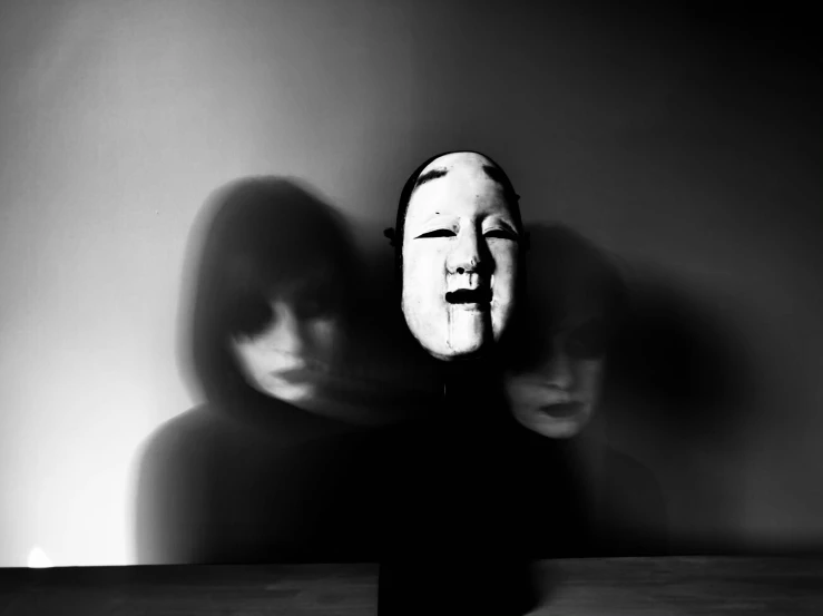 two women behind a doll face on a table
