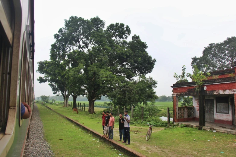 people are standing in the grass beside a train