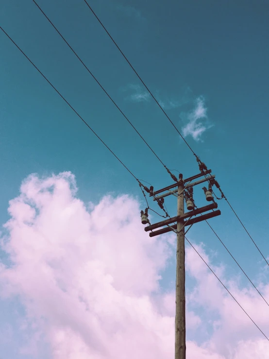 a tall wooden pole has electrical wires under it