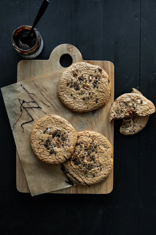 four cookies sit on a board next to a mug