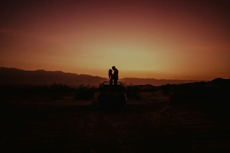 two people on top of a vehicle in the desert