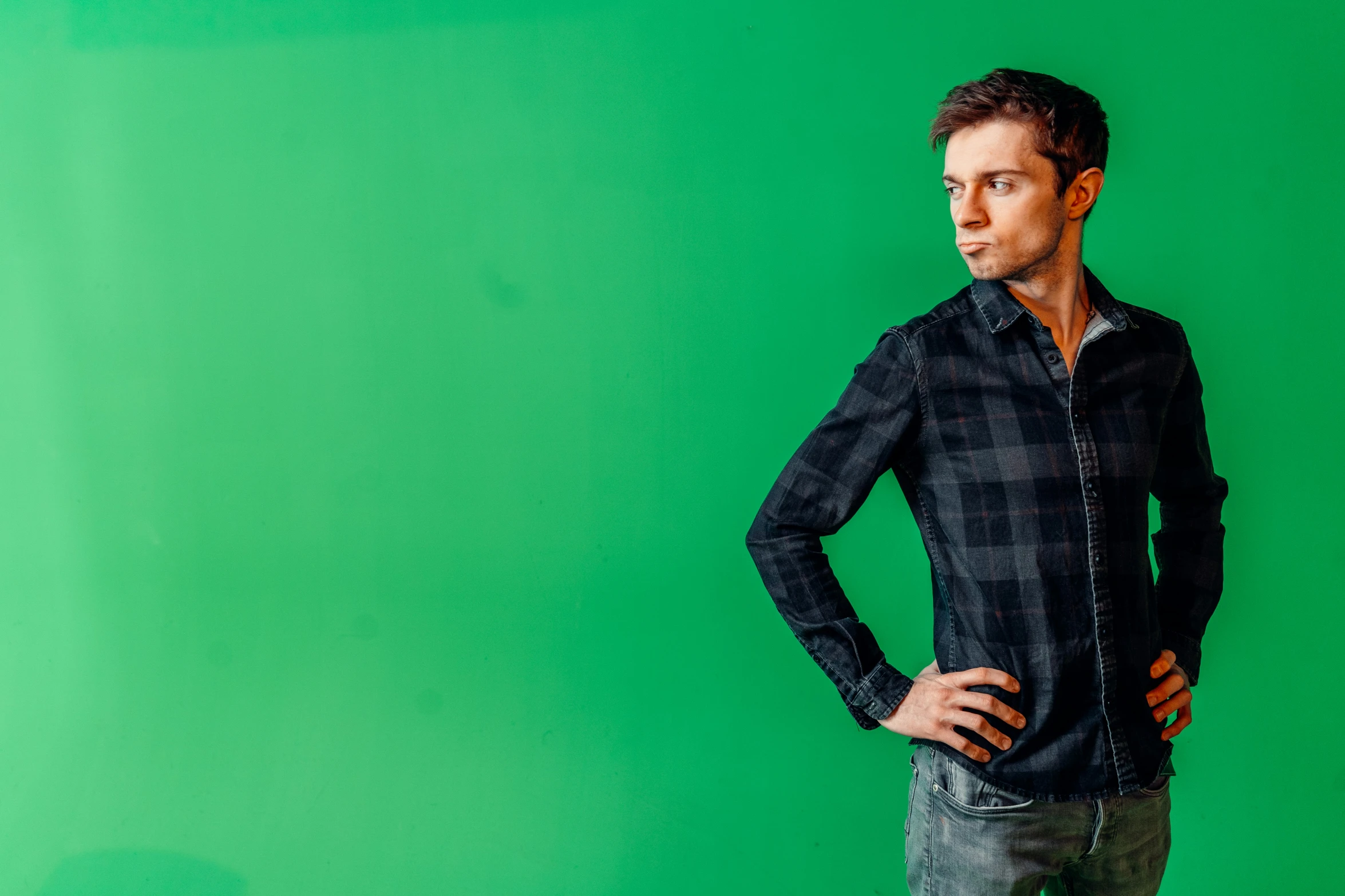 the man in black shirt is posing in front of a green wall