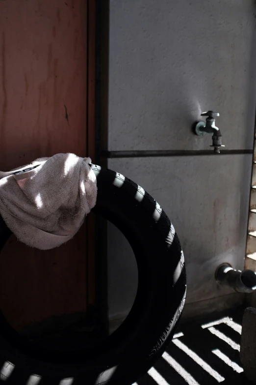 a white towel over a black tire in a restroom