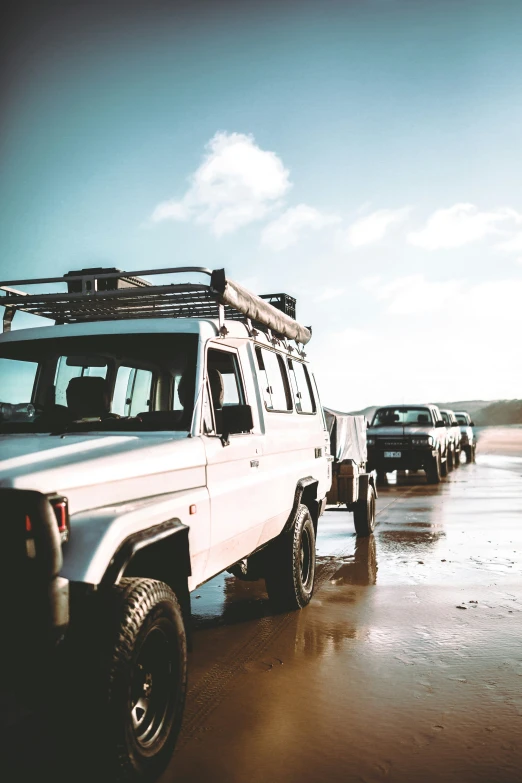 three trucks are parked near each other on the beach