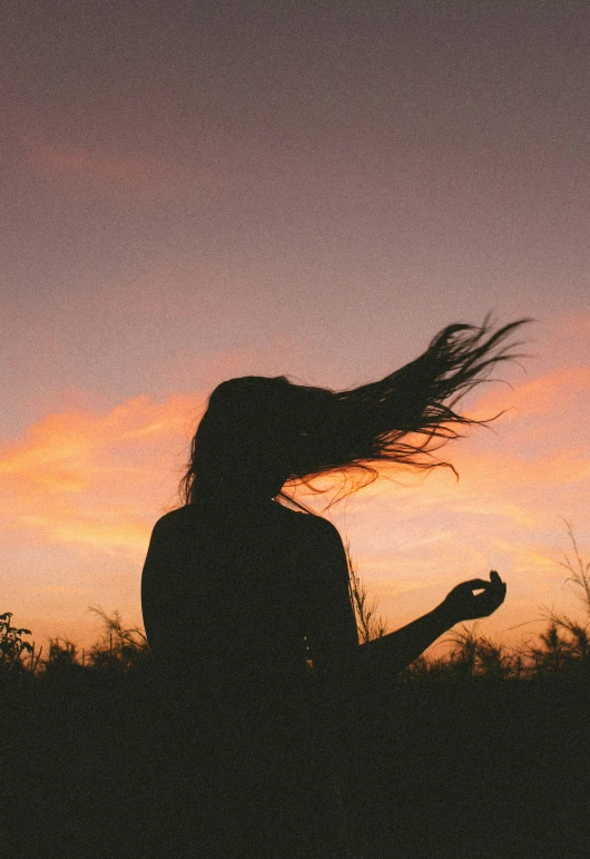 the silhouette of a woman on a hill at sunset