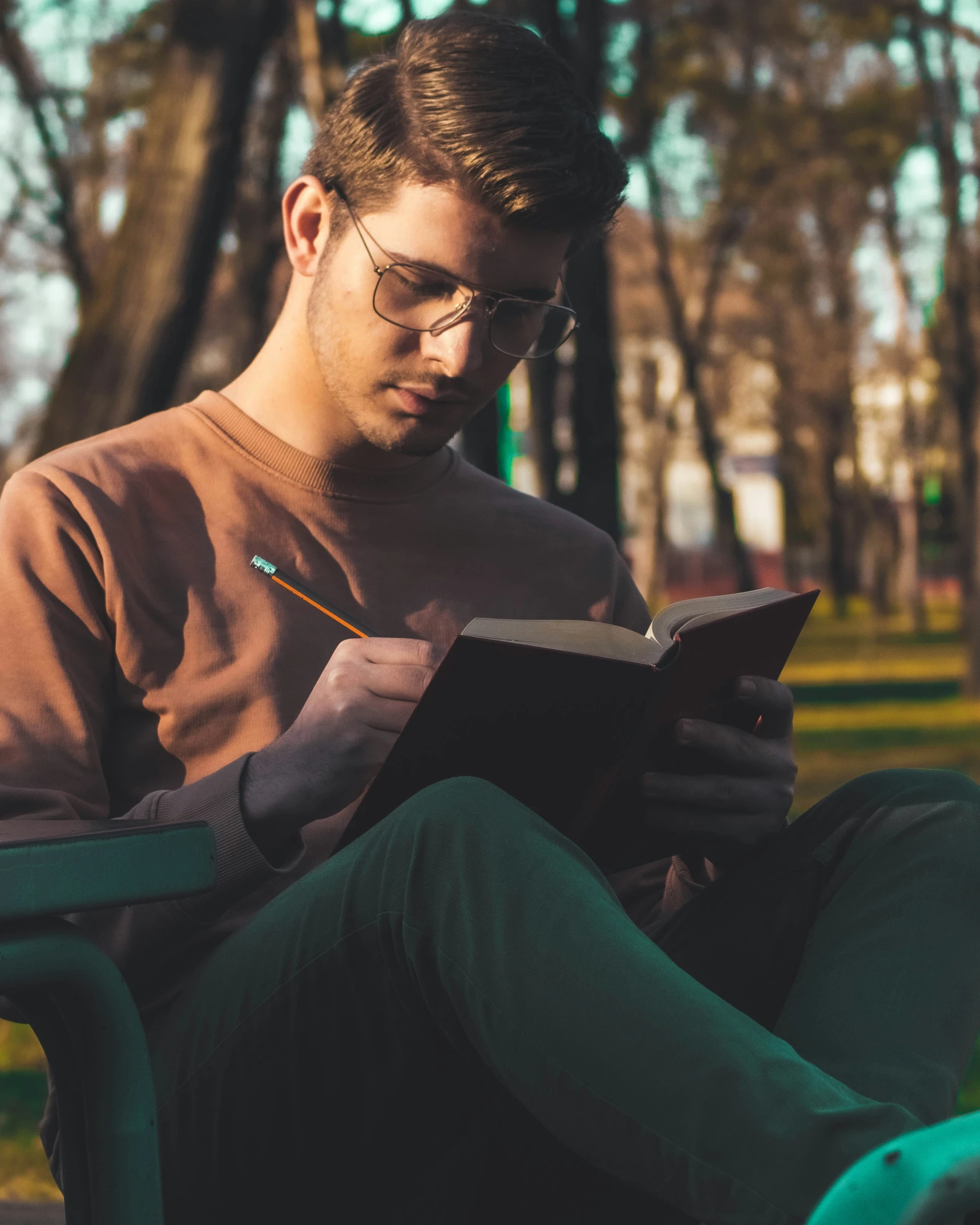 a man in glasses is sitting on a chair while reading a book