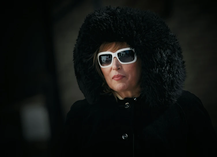 a woman with sunglasses is wearing a black furry hood