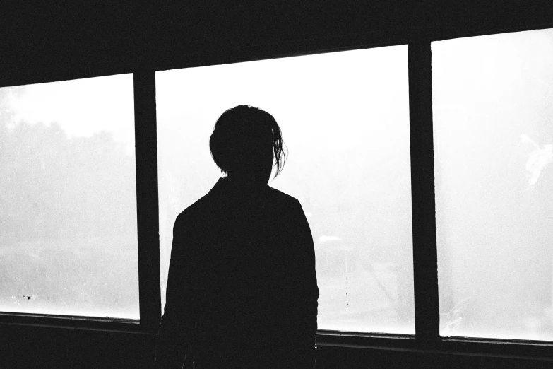a person stands by a window in a dark room