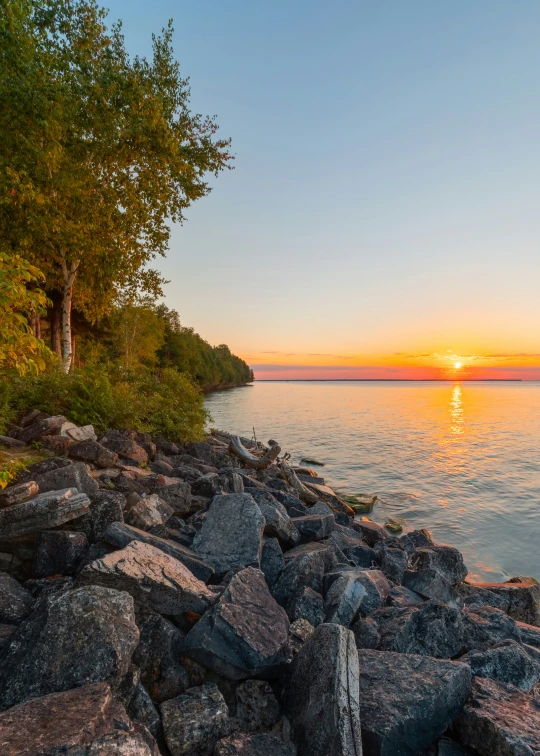 a sunset is pictured as the sun sets over a lake