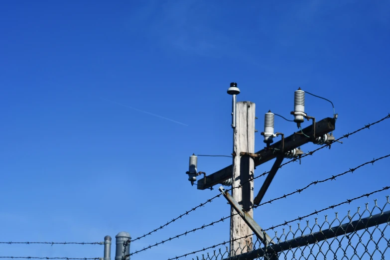 a light post stands behind a barbed wire fence