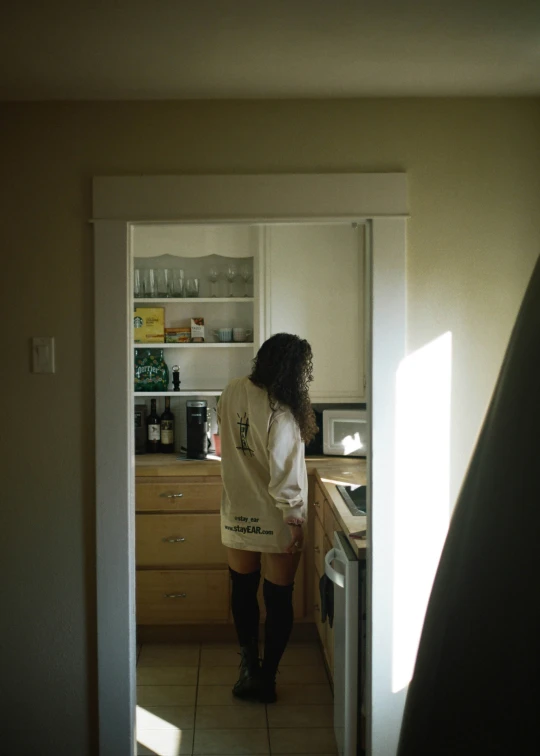 a woman in boots is standing at the kitchen counter