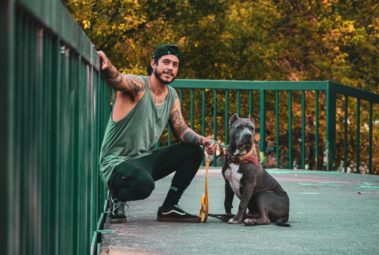 a man sitting with his dog on the side of a green fence