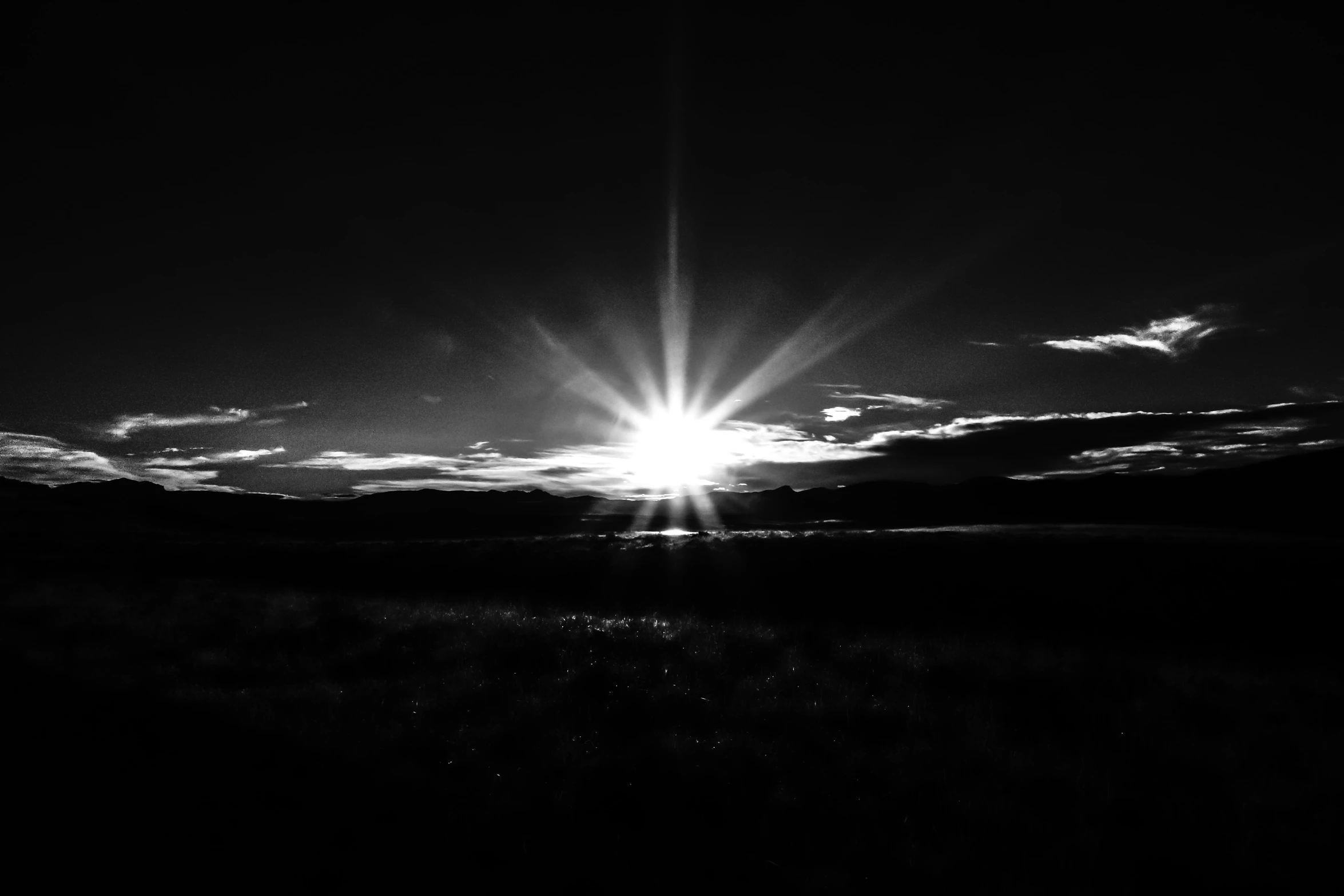 the sun shining over a field near the ocean