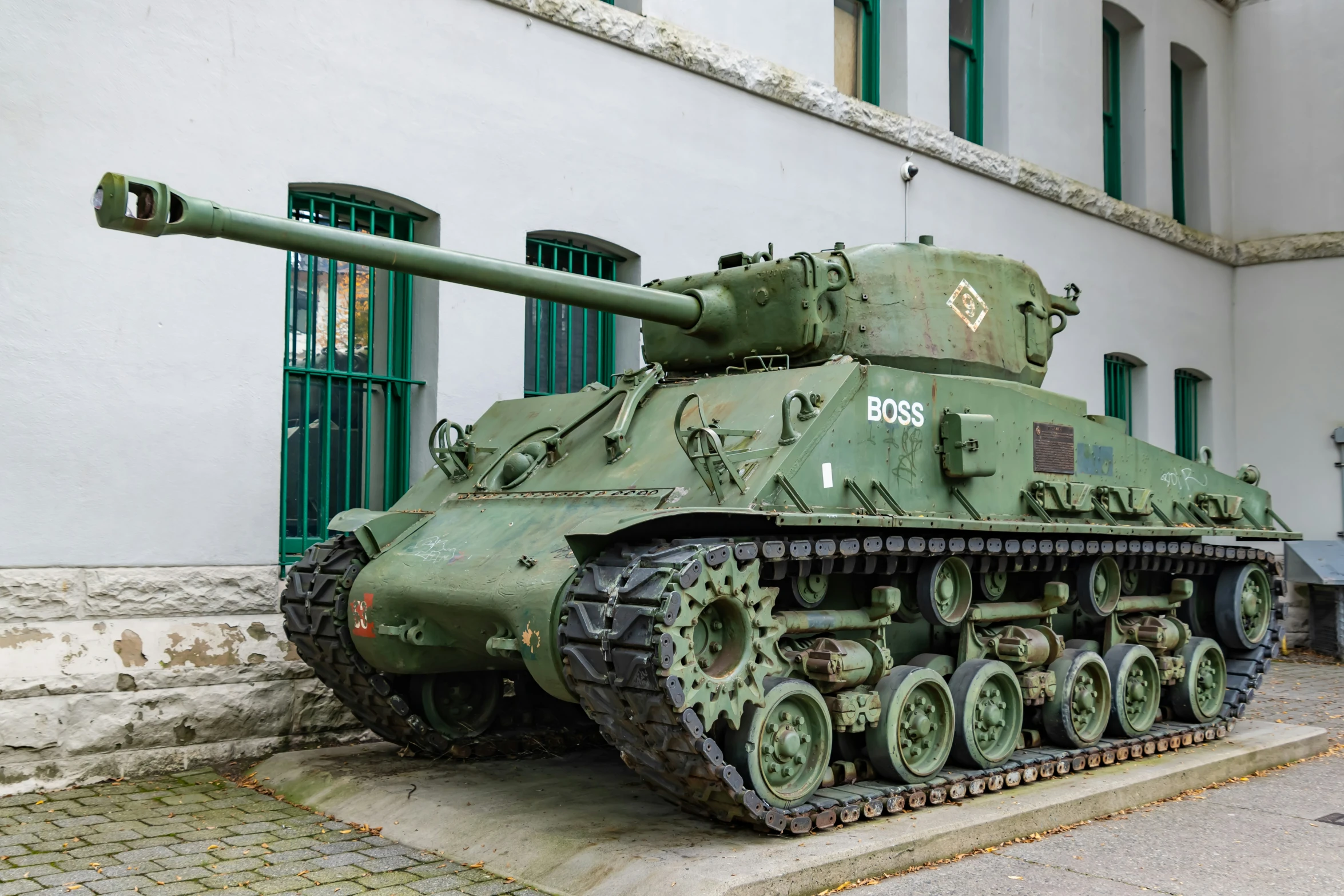 a very large green tank parked on the side of a building