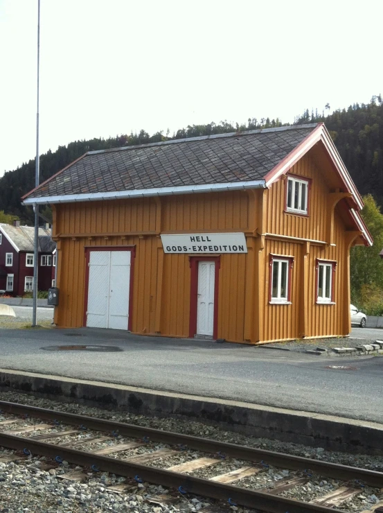 small wooden building next to railroad tracks in rural area