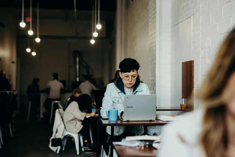 there is a woman sitting at the table working on a laptop