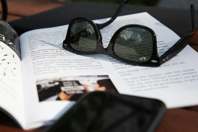 reading glasses resting upon book open with pen and glasses