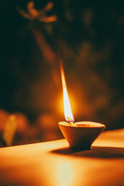 a burning candle on a table in a dark room