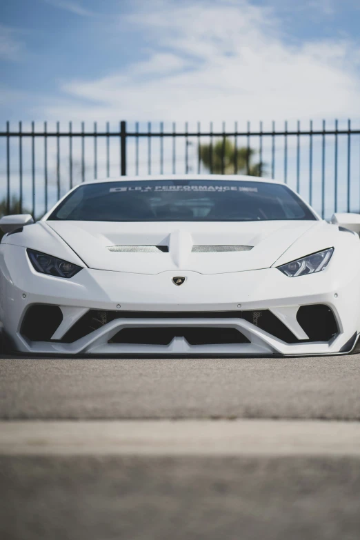 white sports car parked in front of a black fence