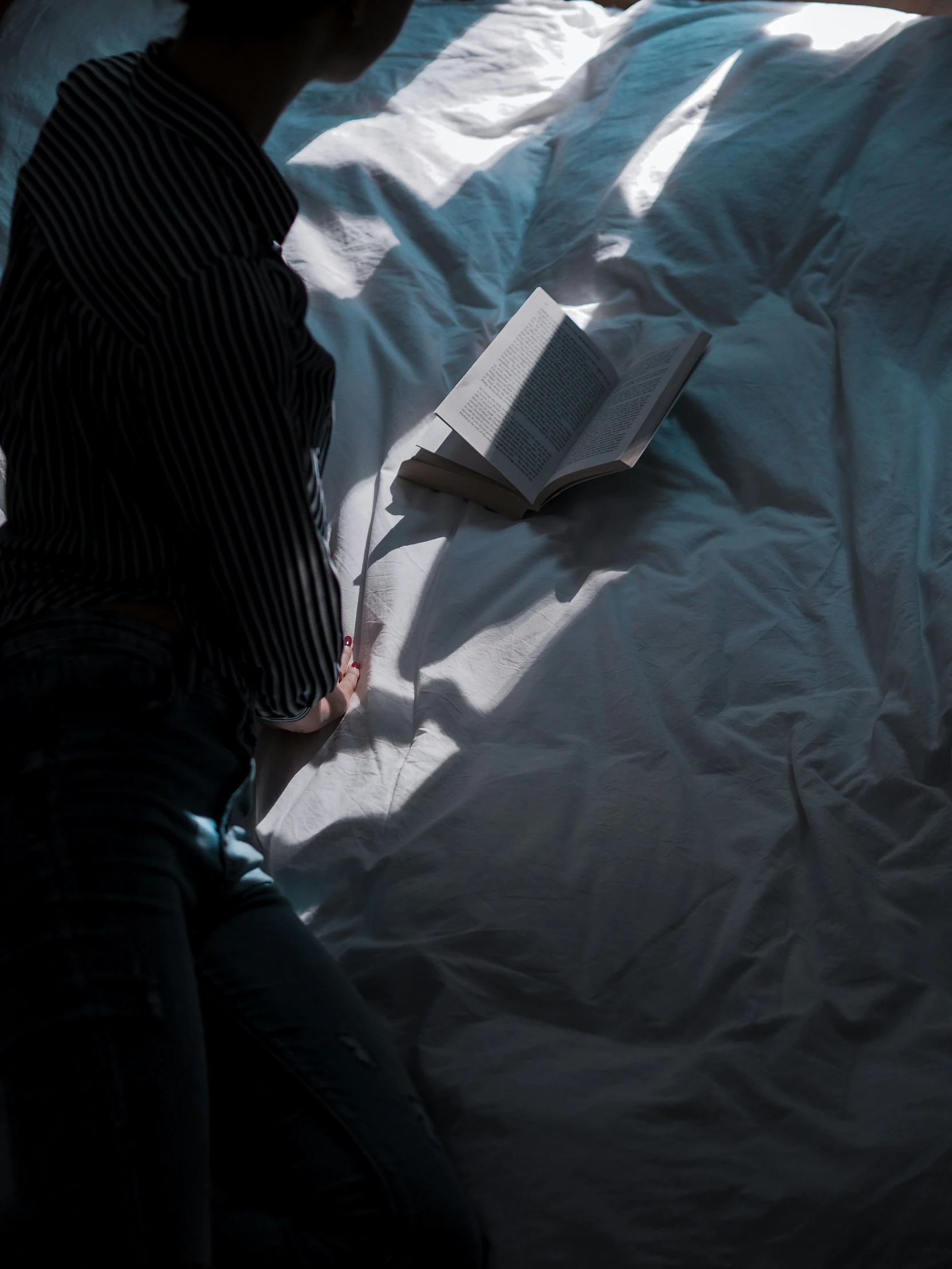 a person in bed reading a book and laying down on the bed