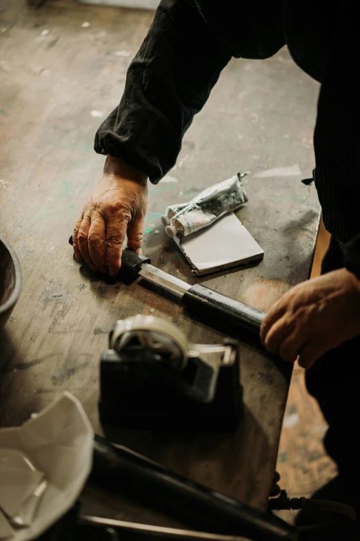 a hand on top of a wooden table with two tools
