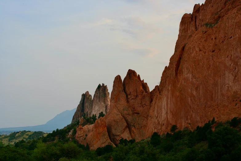 a mountain with several tall rocks near some grass