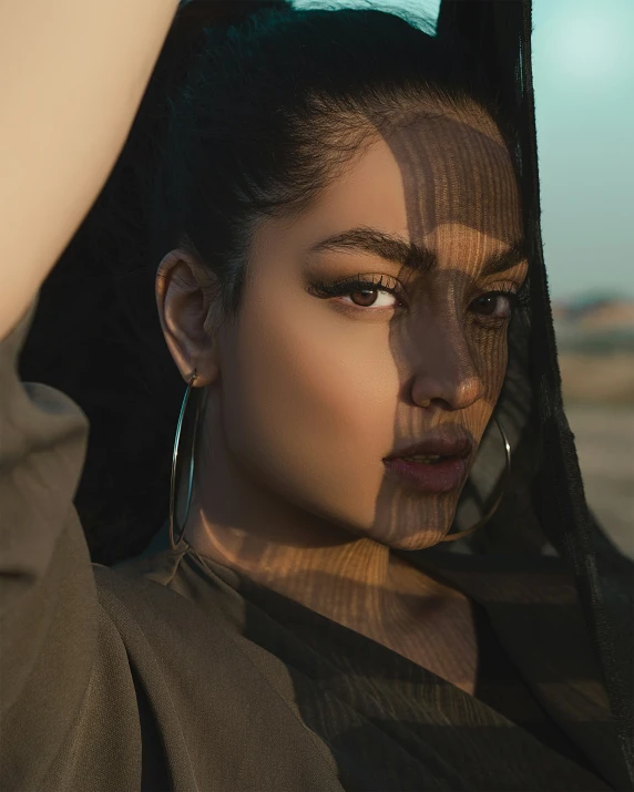 a young woman wearing gold hoop earrings with a sheer covering on her head