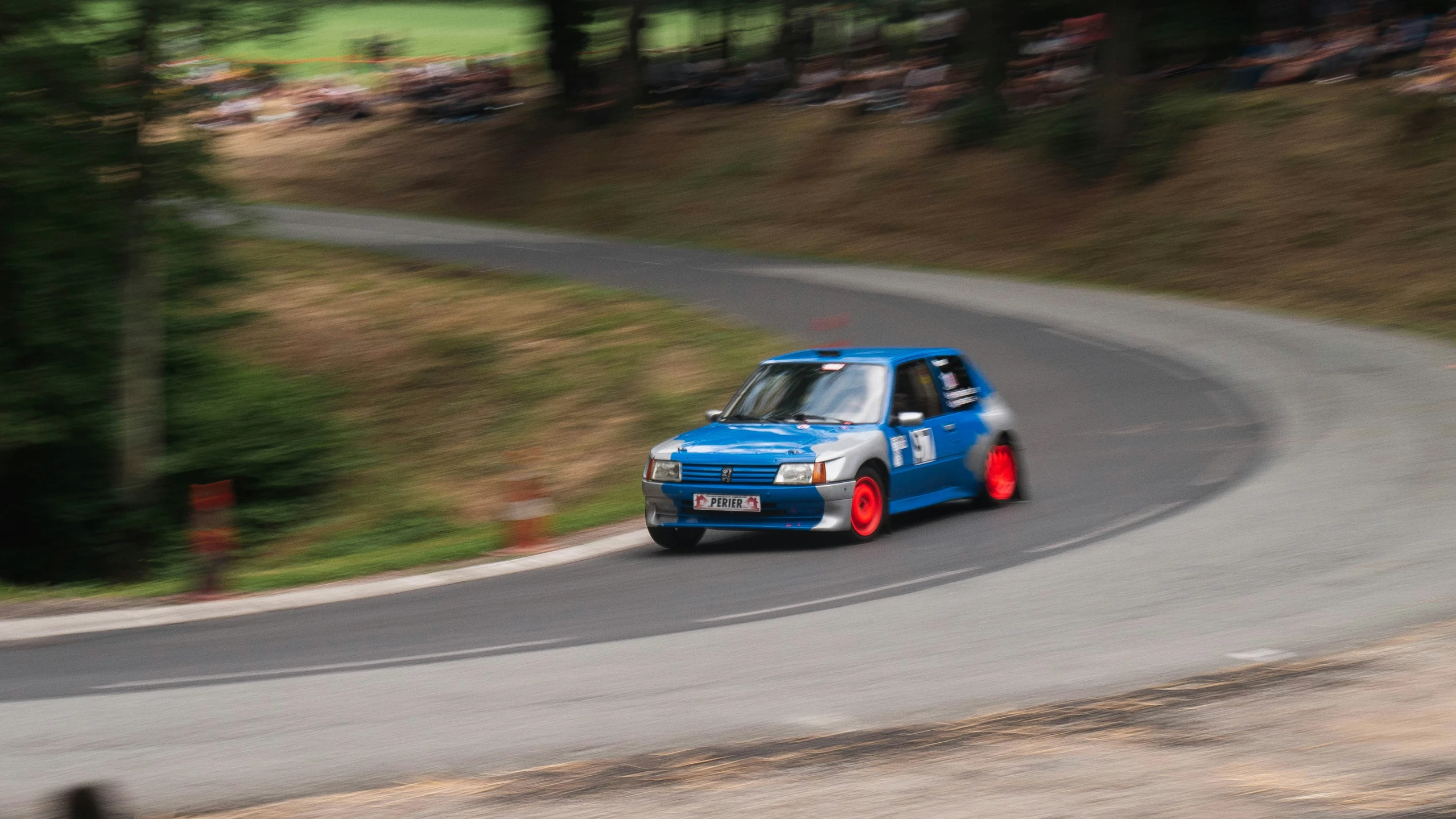 a blue car driving on a road during the day