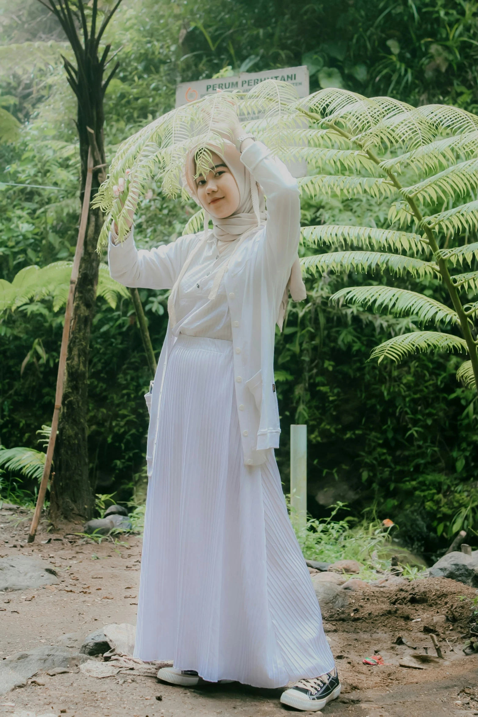 woman in white dress and veil standing next to trees