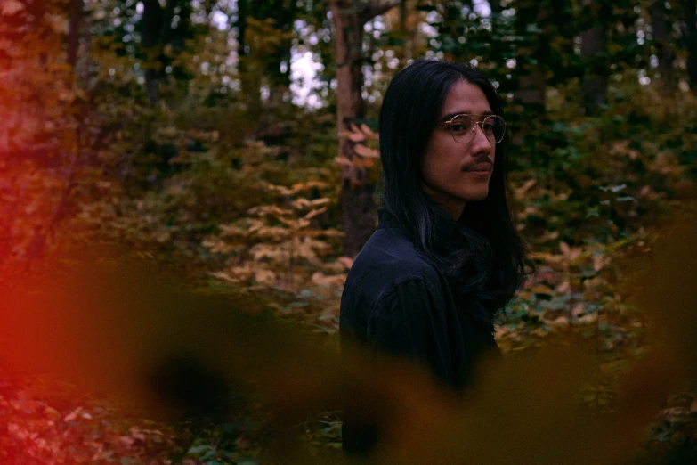 a man in glasses staring into the woods