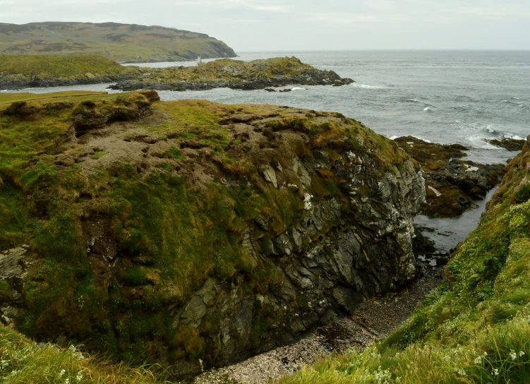 two men walking along the coast near a cliff