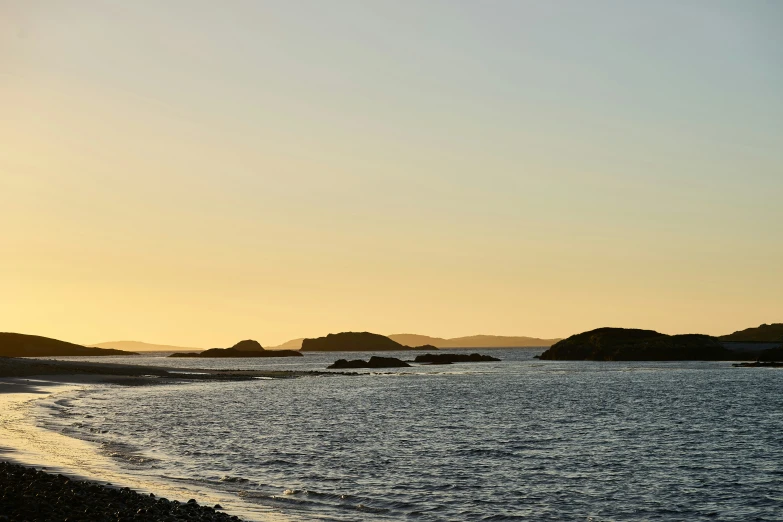 a distant lighthouse on the shoreline in a bay at sunset