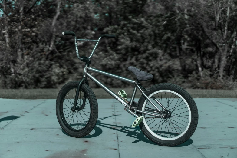 a silver bike in a park near some bushes